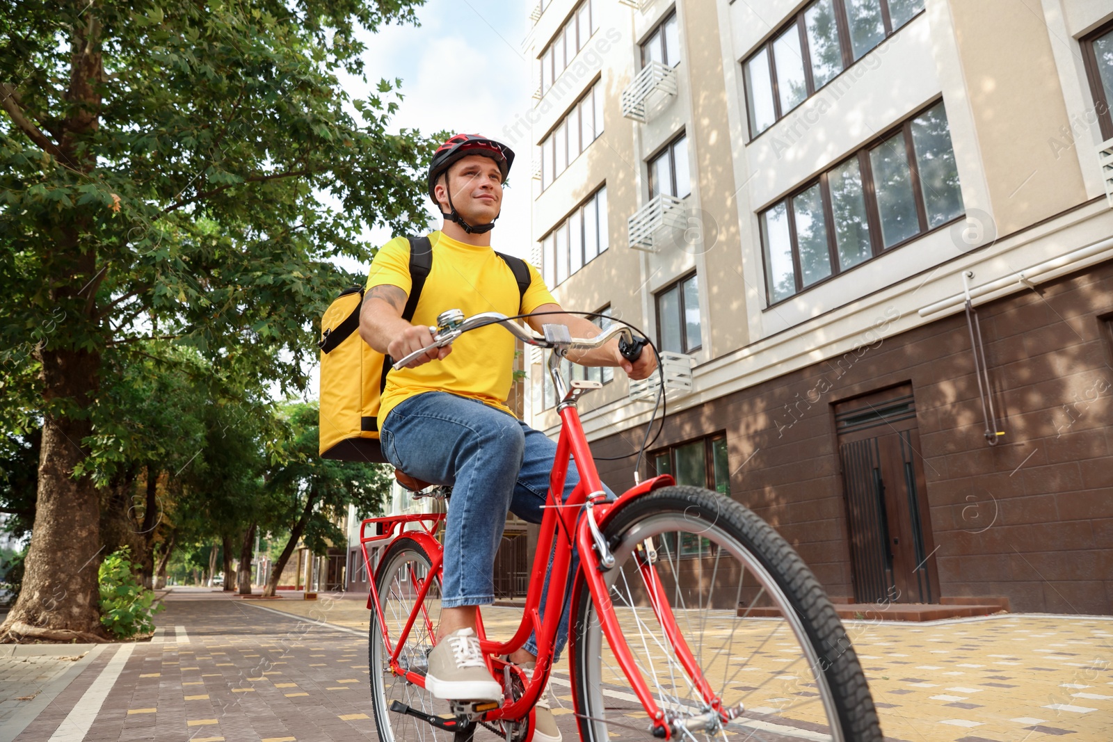 Courier with thermo bag riding bicycle outdoors, low angle view. Food delivery service Photo of Courier with thermo bag riding bicycle outdoors, low angle view. Food delivery service