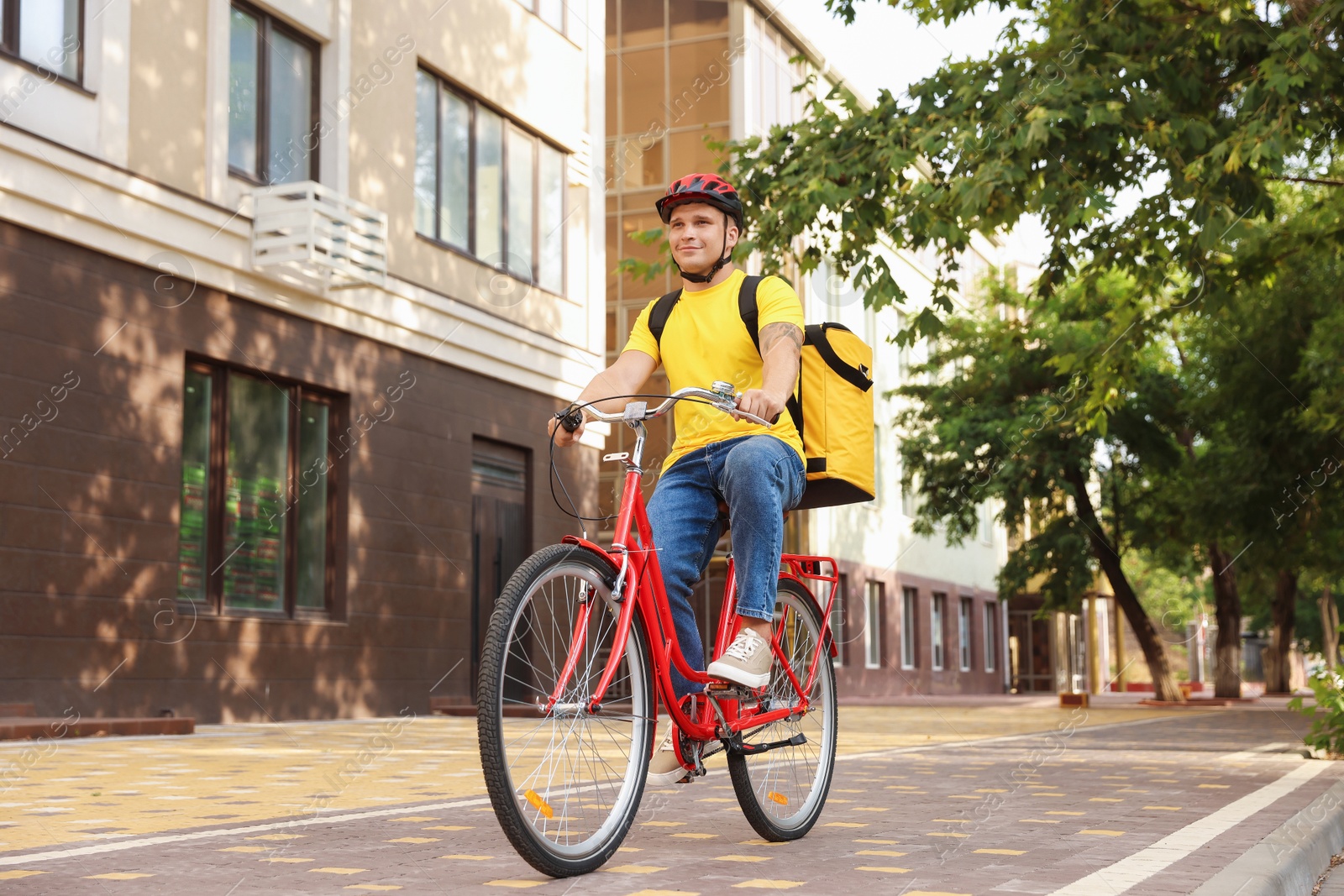 Courier with thermo bag riding bicycle outdoors. Food delivery service Photo of Courier with thermo bag riding bicycle outdoors. Food delivery service