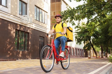 Photo of Courier with thermo bag riding bicycle outdoors. Food delivery service
