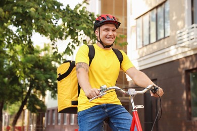 Photo of Courier with thermo bag riding bicycle outdoors. Food delivery service
