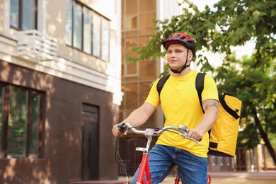 Photo of Courier with thermo bag riding bicycle outdoors, space for text. Food delivery service