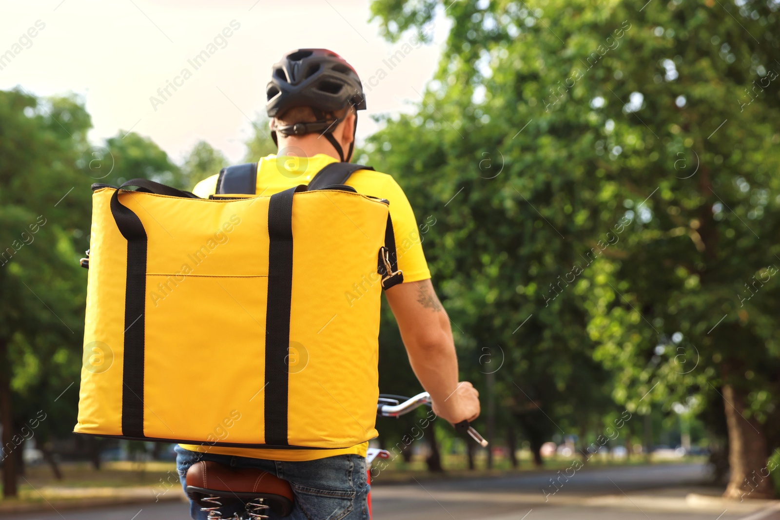 Courier with thermo bag riding bicycle outdoors, back view. Food delivery service Photo of Courier with thermo bag riding bicycle outdoors, back view. Food delivery service