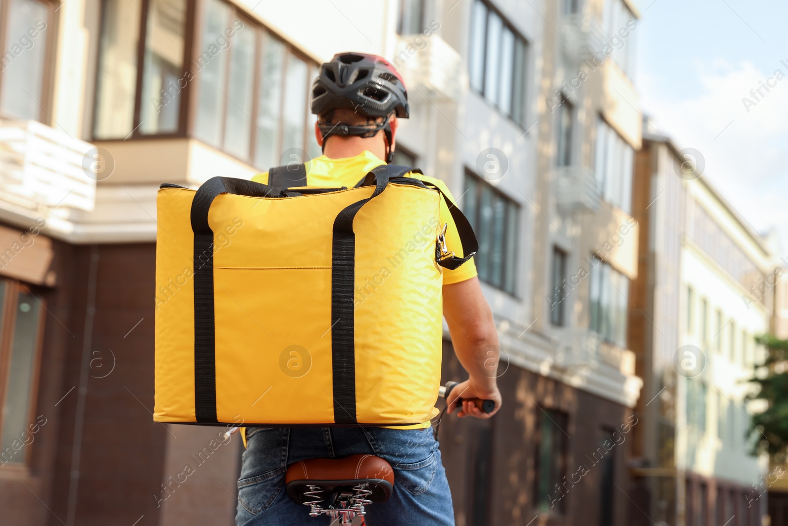 Courier with thermo bag riding bicycle outdoors, back view. Food delivery service Photo of Courier with thermo bag riding bicycle outdoors, back view. Food delivery service