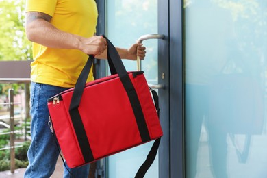 Photo of Courier with thermo bag near door outdoors, closeup. Food delivery service