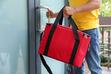 Photo of Courier with thermo bag near door outdoors, closeup. Food delivery service