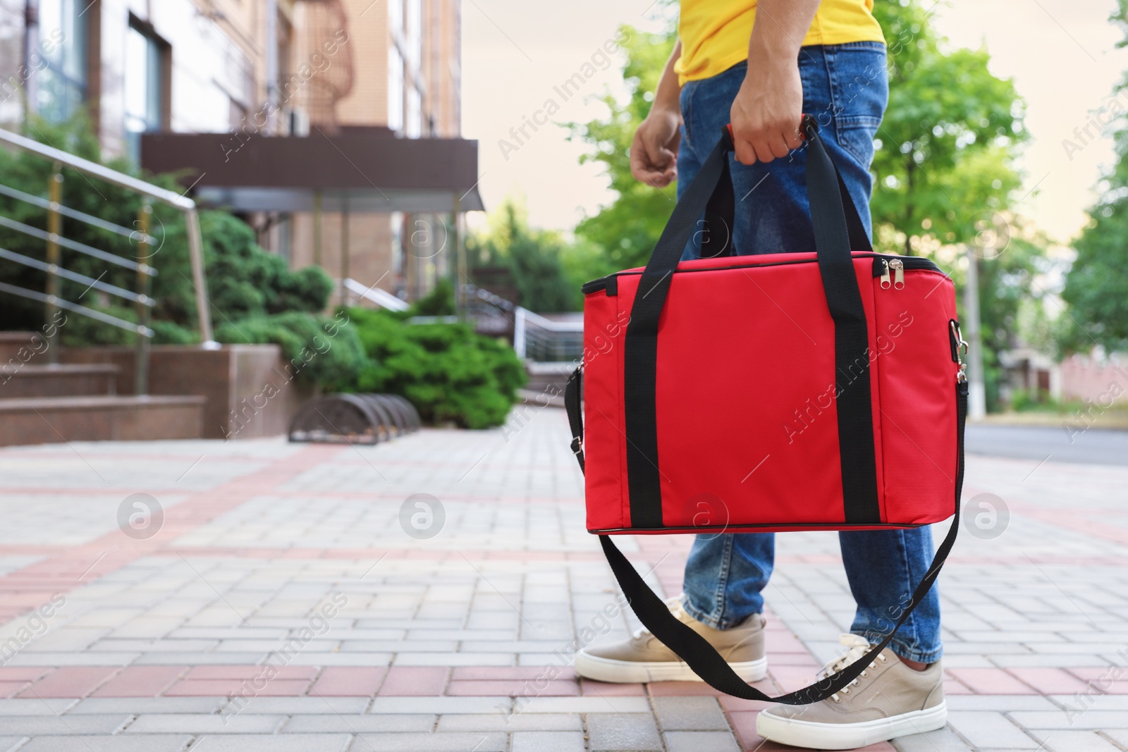 Courier with thermo bag on city street, closeup. Food delivery service Photo of Courier with thermo bag on city street, closeup. Food delivery service