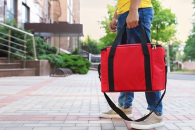 Photo of Courier with thermo bag on city street, closeup. Food delivery service
