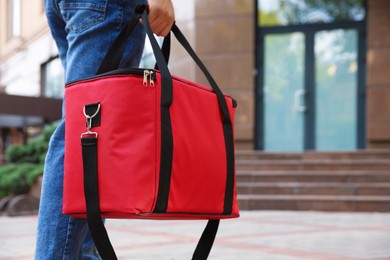 Photo of Courier with thermo bag on city street, closeup. Food delivery service