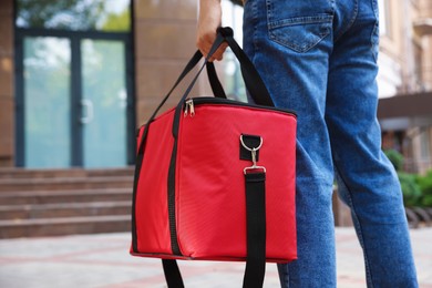 Photo of Courier with thermo bag on city street, closeup. Food delivery service