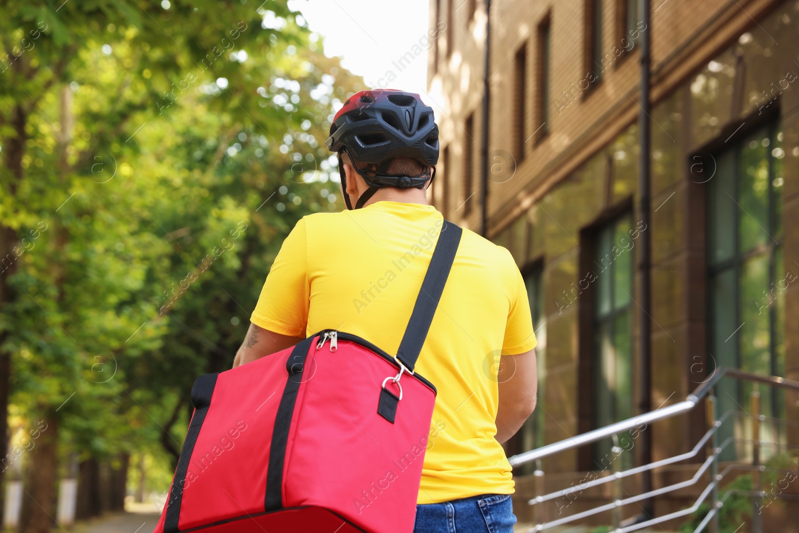 Courier with thermo bag riding bicycle outdoors, back view. Food delivery service Photo of Courier with thermo bag riding bicycle outdoors, back view. Food delivery service
