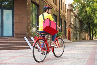 Photo of Courier with thermo bag riding bicycle outdoors. Food delivery service