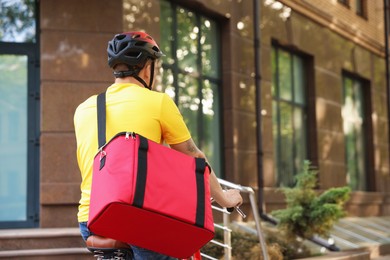 Photo of Courier with thermo bag riding bicycle outdoors, space for text. Food delivery service