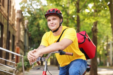 Photo of Courier with thermo bag on bicycle outdoors. Food delivery service
