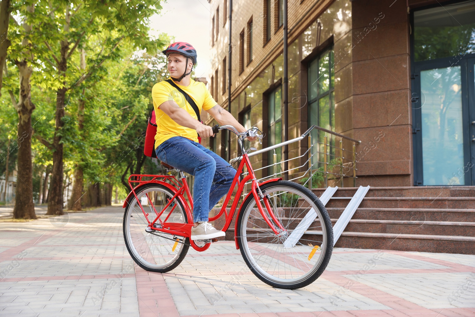 Courier with thermo bag riding bicycle outdoors. Food delivery service Photo of Courier with thermo bag riding bicycle outdoors. Food delivery service