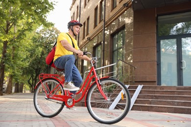 Photo of Courier with thermo bag riding bicycle outdoors, low angle view. Food delivery service