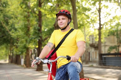 Photo of Courier with thermo bag riding bicycle outdoors. Food delivery service