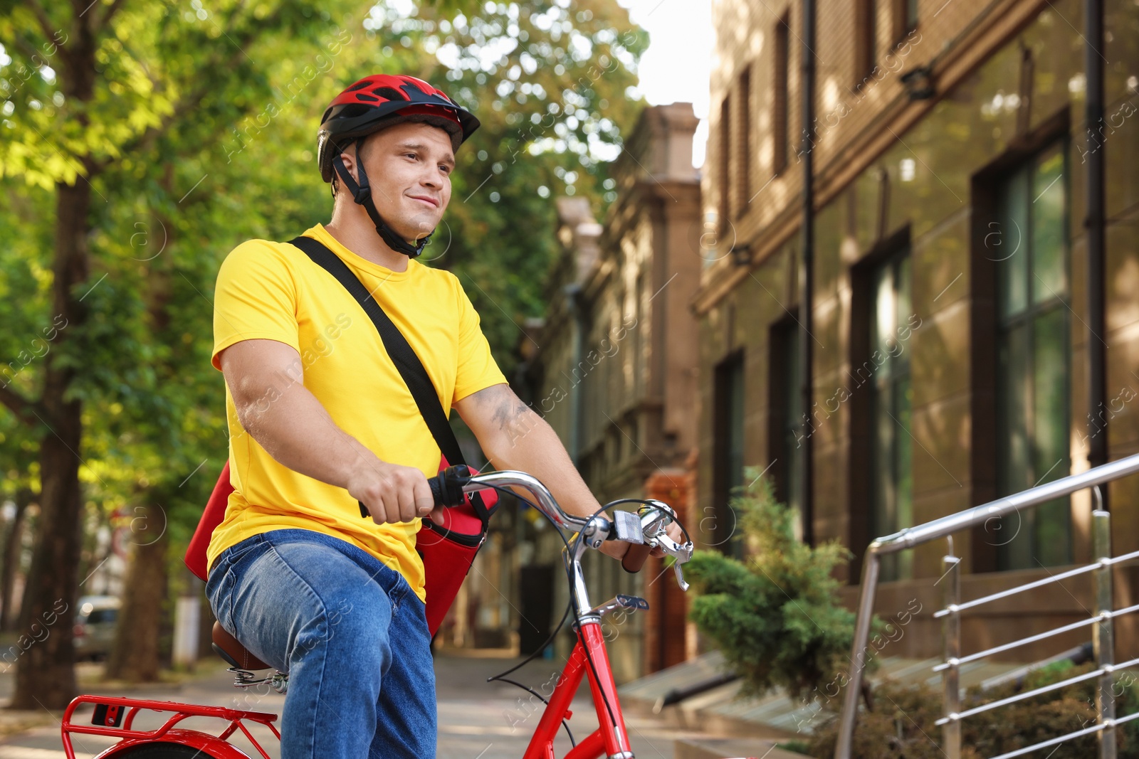Courier with thermo bag riding bicycle outdoors. Food delivery service Photo of Courier with thermo bag riding bicycle outdoors. Food delivery service