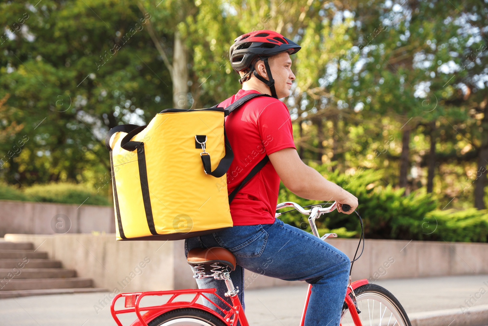 Courier with thermo bag riding bicycle outdoors. Food delivery service Photo of Courier with thermo bag riding bicycle outdoors. Food delivery service