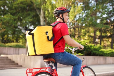 Photo of Courier with thermo bag riding bicycle outdoors. Food delivery service