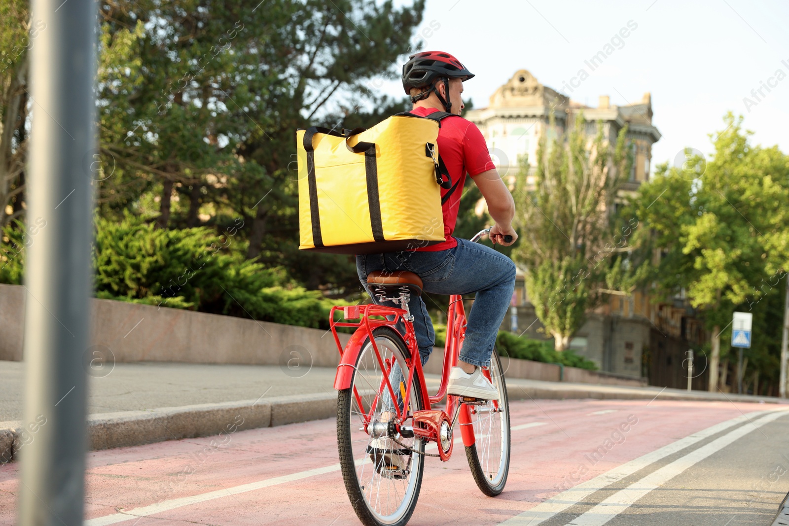Courier with thermo bag riding bicycle outdoors. Food delivery service Photo of Courier with thermo bag riding bicycle outdoors. Food delivery service