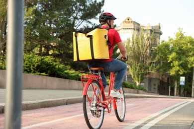 Photo of Courier with thermo bag riding bicycle outdoors. Food delivery service