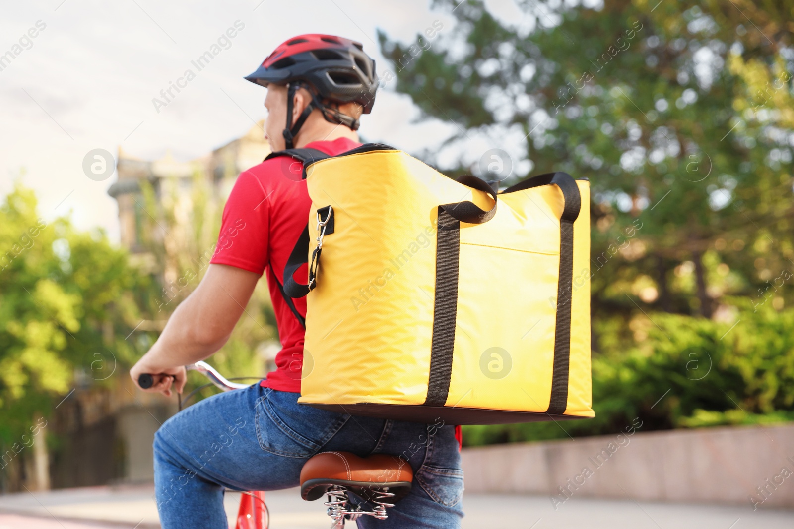 Courier with thermo bag riding bicycle outdoors. Food delivery service Photo of Courier with thermo bag riding bicycle outdoors. Food delivery service