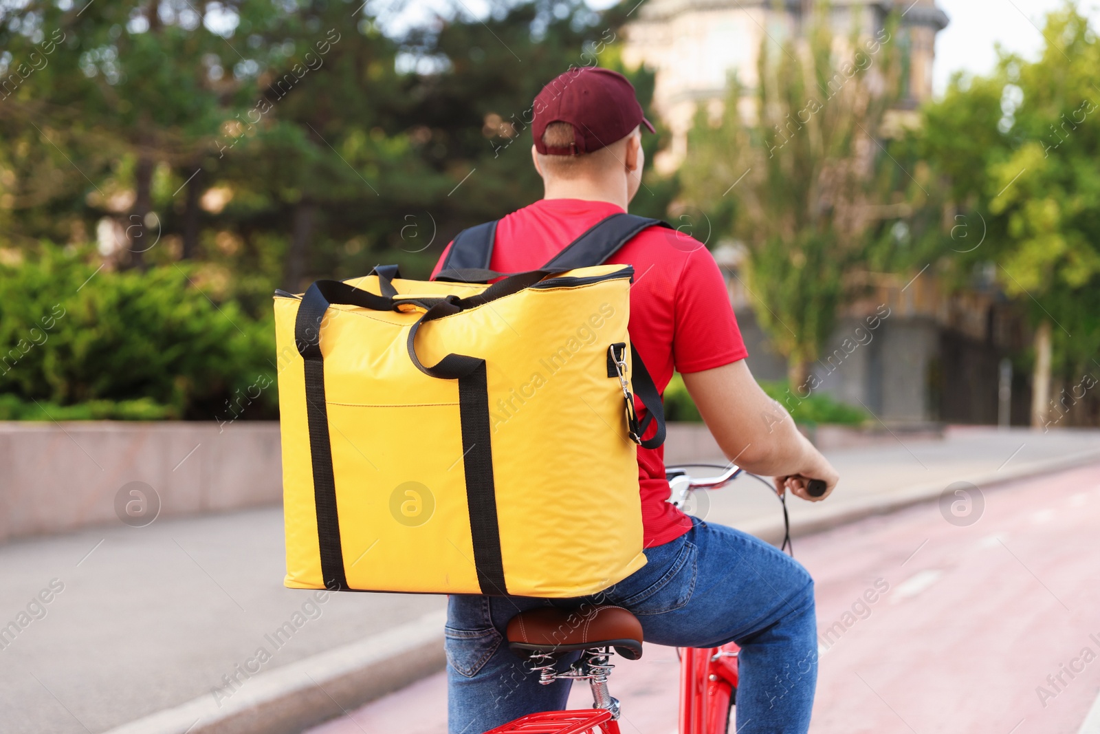 Courier with thermo bag riding bicycle outdoors, back view. Food delivery service Photo of Courier with thermo bag riding bicycle outdoors, back view. Food delivery service