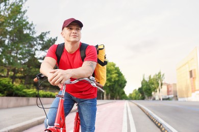 Photo of Courier with thermo bag on bicycle outdoors, space for text. Food delivery service