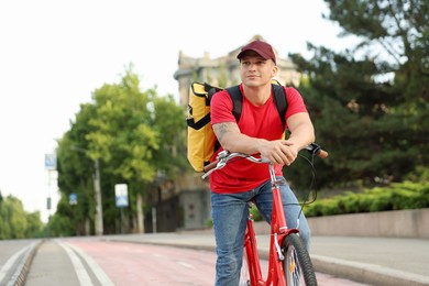 Photo of Courier with thermo bag riding bicycle outdoors, space for text. Food delivery service