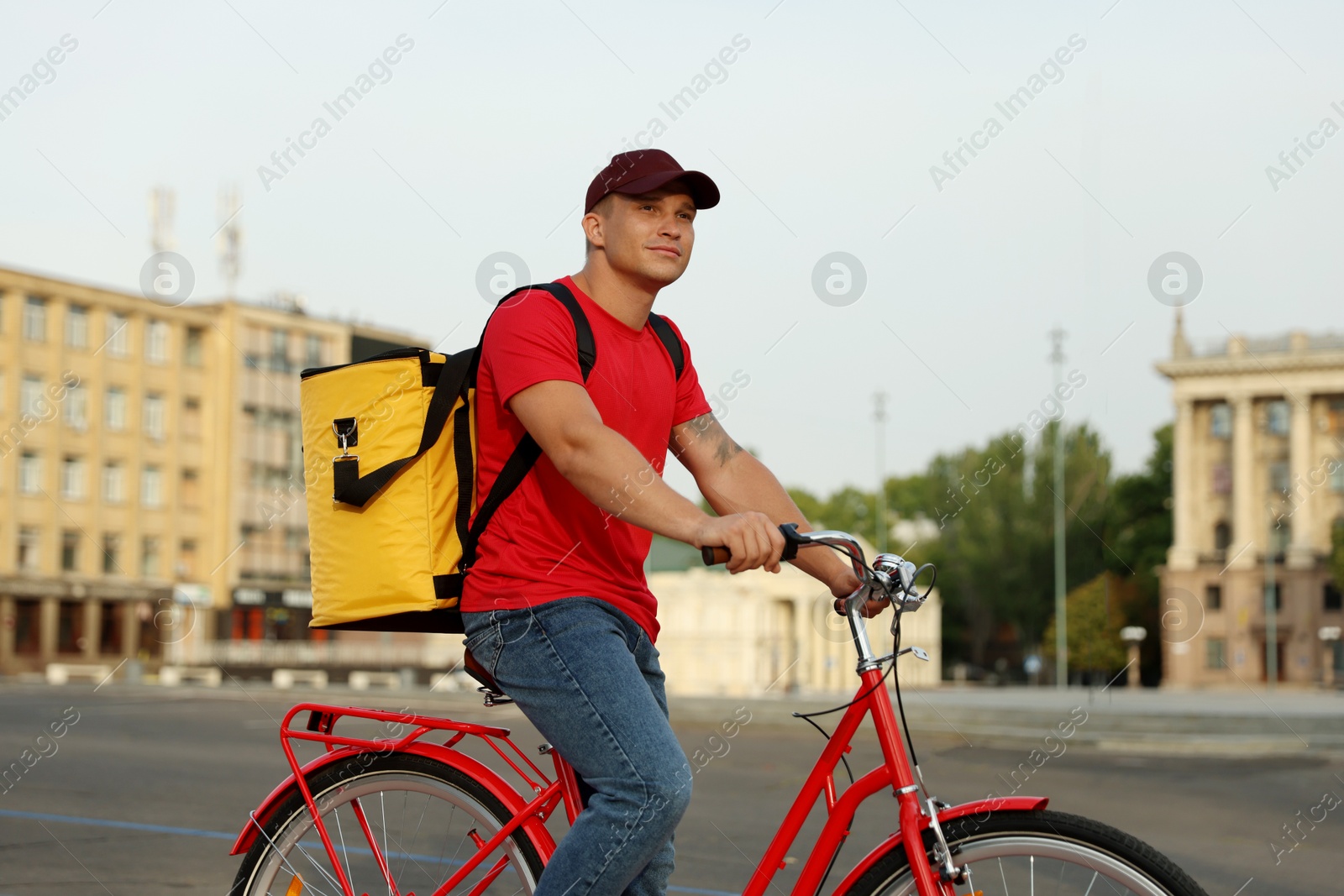 Courier with thermo bag riding bicycle outdoors. Food delivery service Photo of Courier with thermo bag riding bicycle outdoors. Food delivery service
