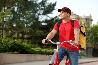 Photo of Courier with thermo bag riding bicycle outdoors, space for text. Food delivery service