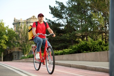 Photo of Courier with thermo bag riding bicycle outdoors, space for text. Food delivery service
