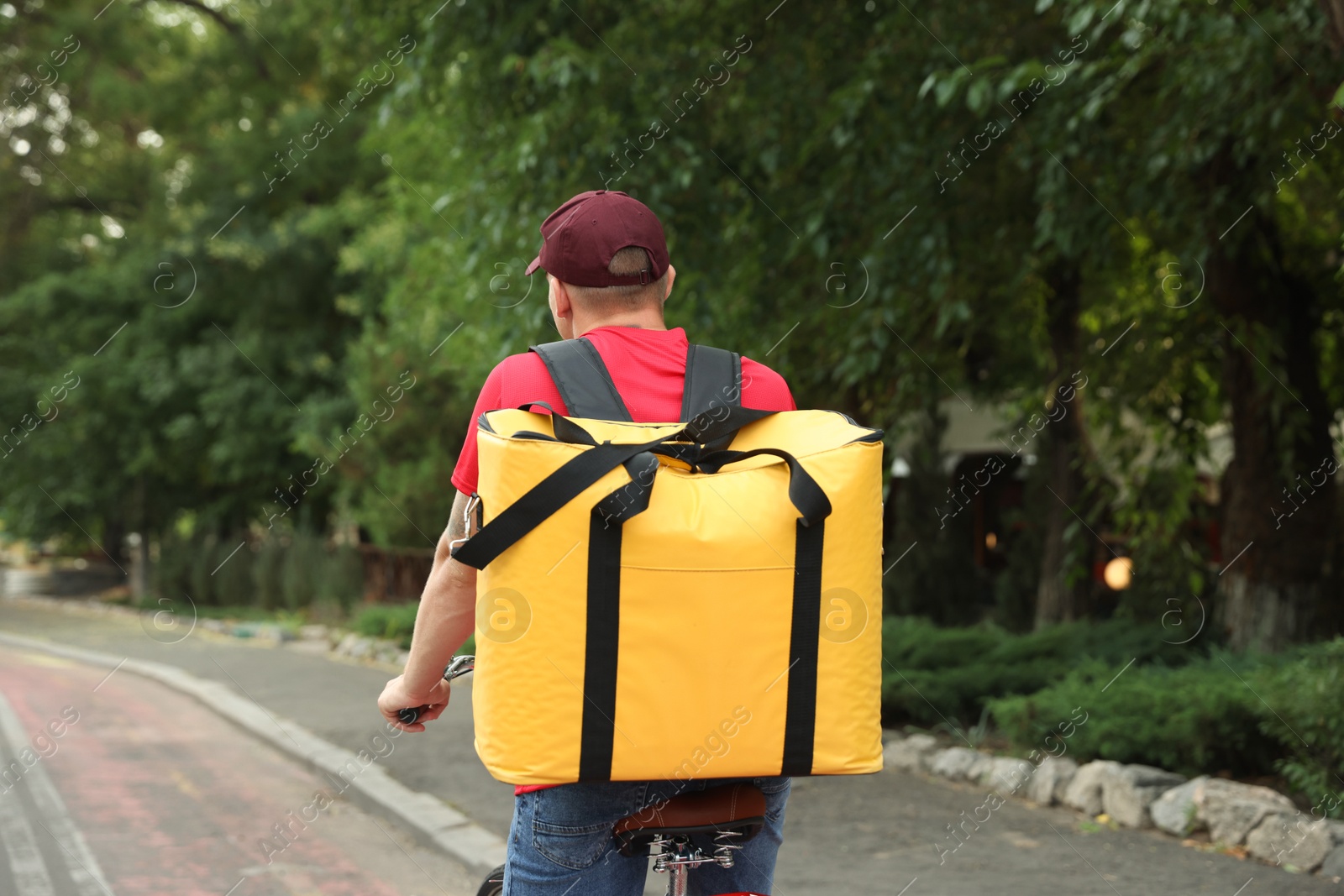 Courier with thermo bag riding bicycle outdoors, back view. Food delivery service Photo of Courier with thermo bag riding bicycle outdoors, back view. Food delivery service