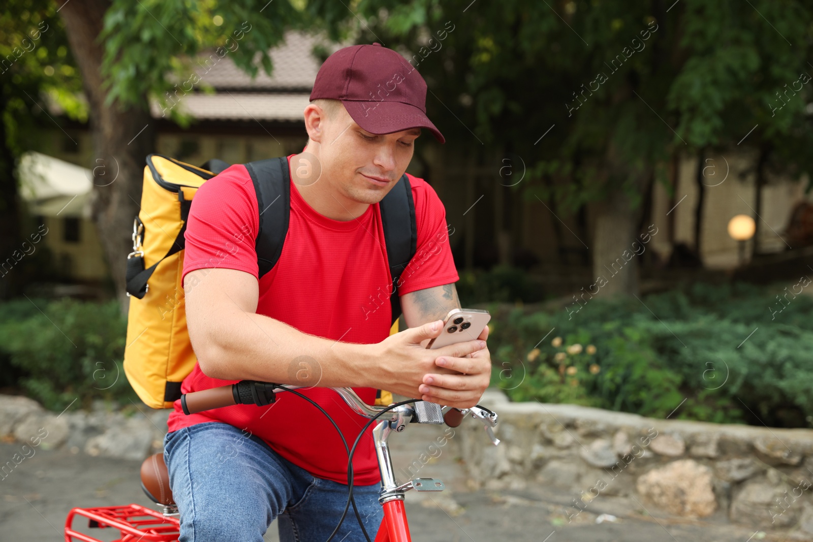 Courier with thermo bag and smartphone on bicycle outdoors, space for text. Food delivery service Photo of Courier with thermo bag and smartphone on bicycle outdoors, space for text. Food delivery service