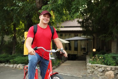 Photo of Courier with thermo bag on bicycle outdoors, space for text. Food delivery service