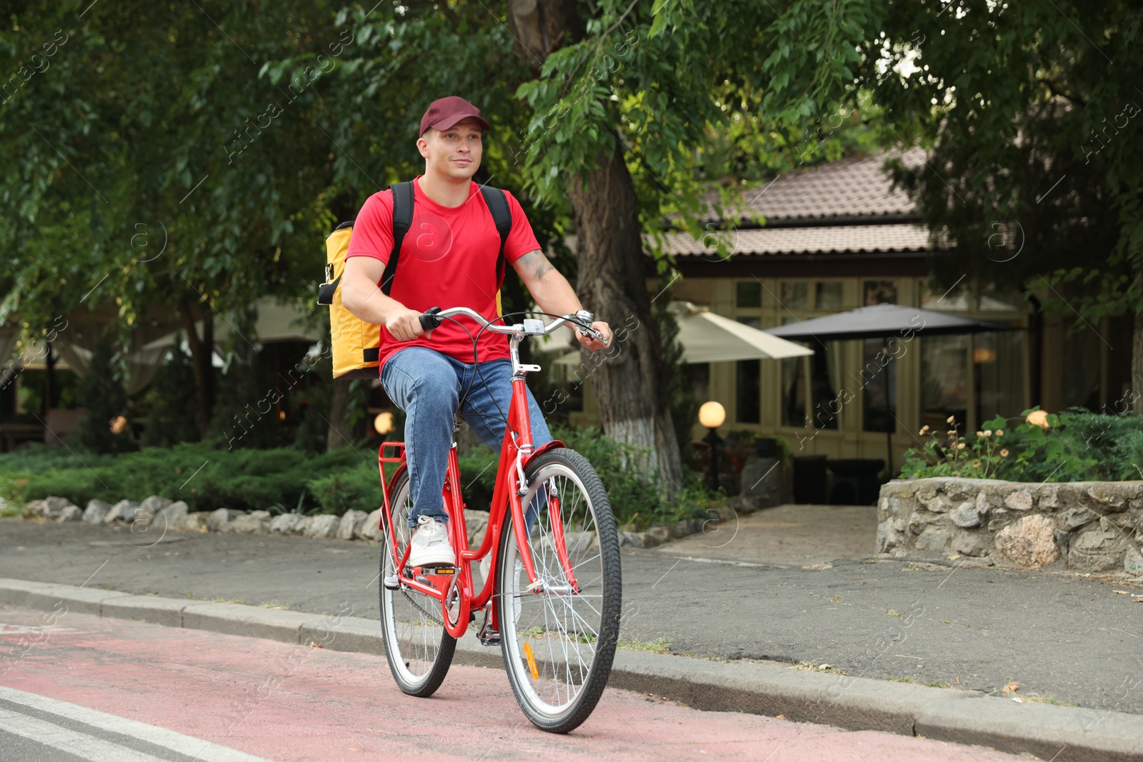 Courier with thermo bag riding bicycle outdoors. Food delivery service Photo of Courier with thermo bag riding bicycle outdoors. Food delivery service