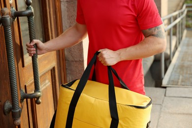 Photo of Courier with thermo bag near door outdoors, closeup. Food delivery service