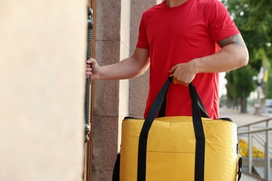 Photo of Courier with thermo bag near door outdoors, closeup. Food delivery service