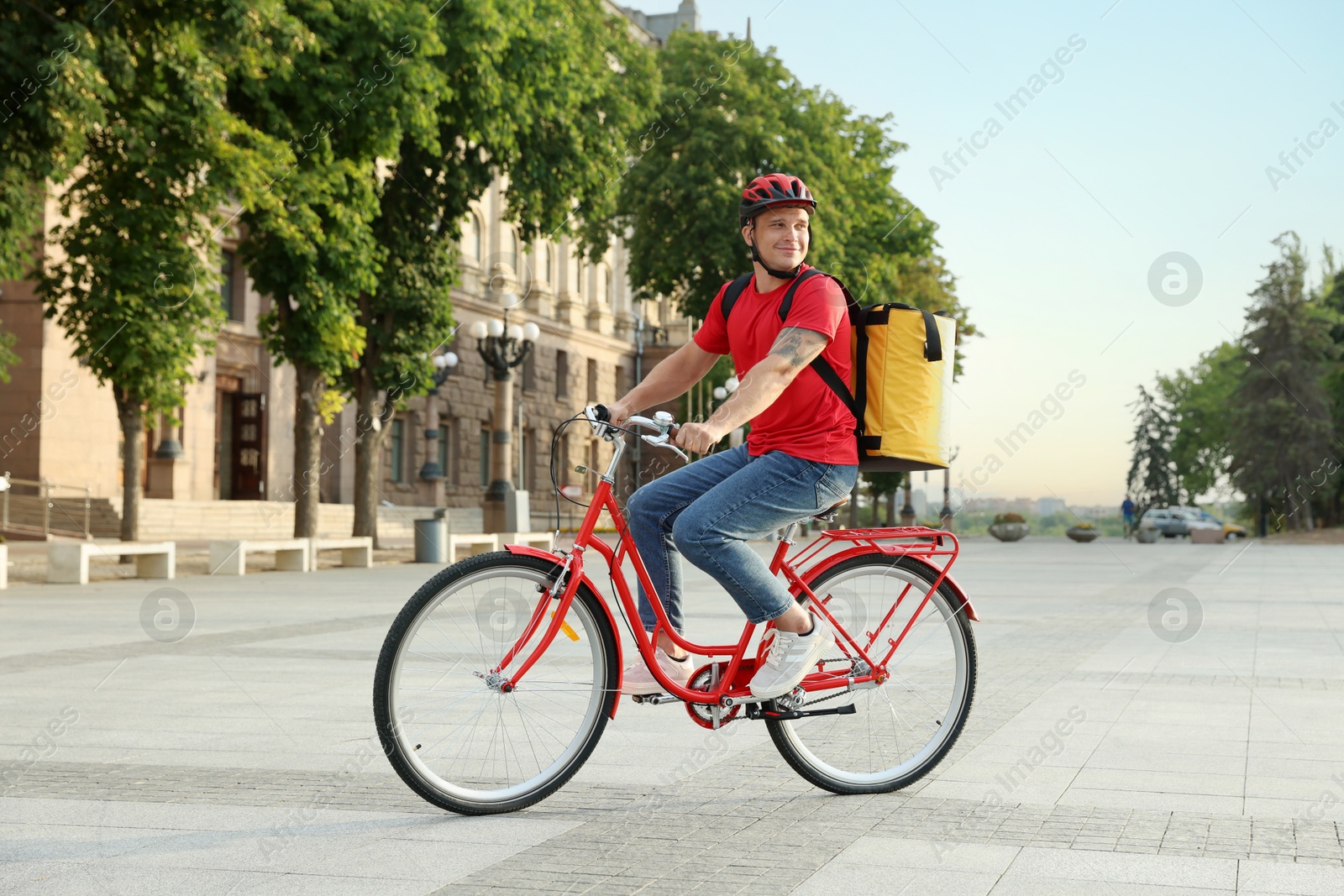 Courier with thermo bag riding bicycle outdoors. Food delivery service Photo of Courier with thermo bag riding bicycle outdoors. Food delivery service