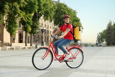 Photo of Courier with thermo bag riding bicycle outdoors. Food delivery service
