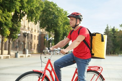 Photo of Courier with thermo bag on bicycle outdoors. Food delivery service