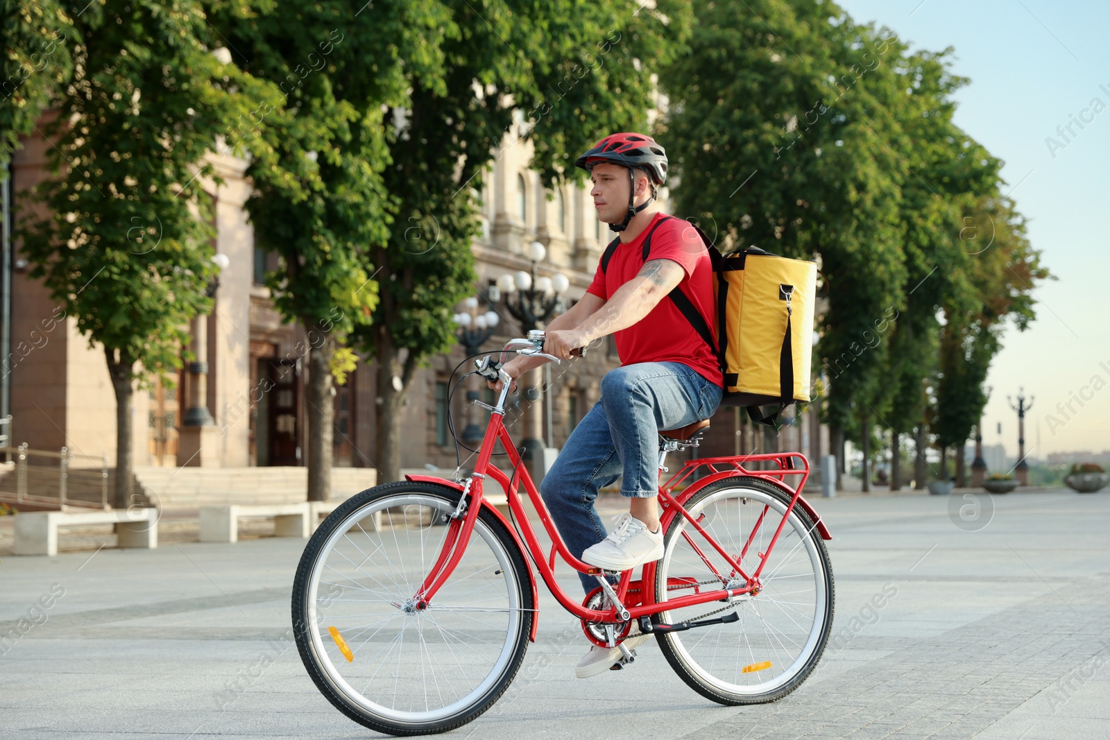 Courier with thermo bag riding bicycle outdoors. Food delivery service Photo of Courier with thermo bag riding bicycle outdoors. Food delivery service