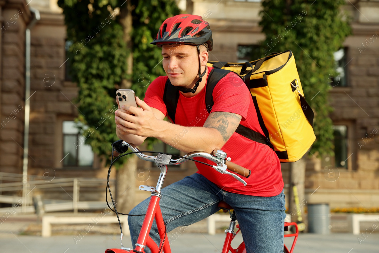 Courier with thermo bag and smartphone on bicycle outdoors. Food delivery service Photo of Courier with thermo bag and smartphone on bicycle outdoors. Food delivery service