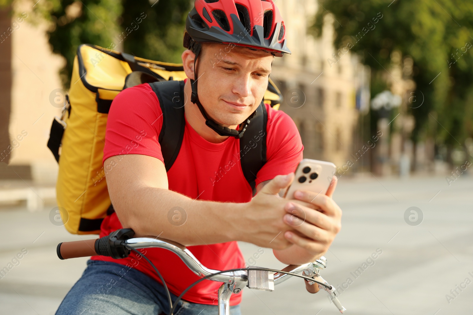 Courier with thermo bag and smartphone on bicycle outdoors. Food delivery service Photo of Courier with thermo bag and smartphone on bicycle outdoors. Food delivery service