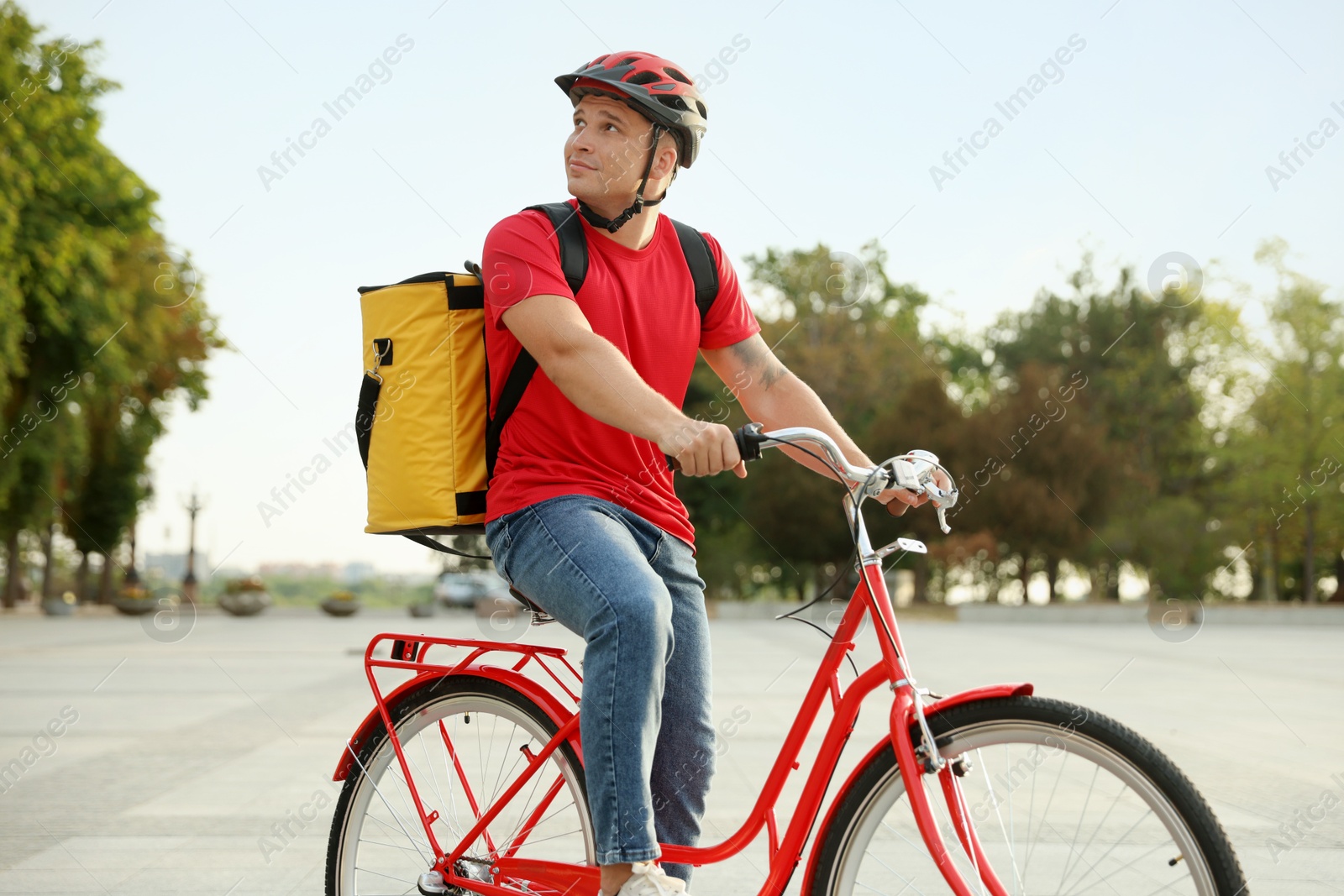 Courier with thermo bag riding bicycle outdoors. Food delivery service Photo of Courier with thermo bag riding bicycle outdoors. Food delivery service