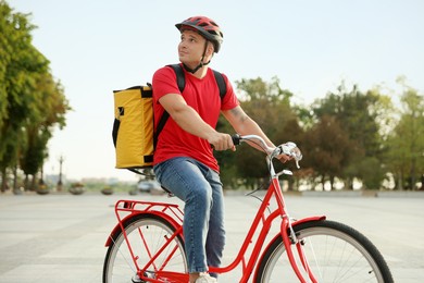 Photo of Courier with thermo bag riding bicycle outdoors. Food delivery service