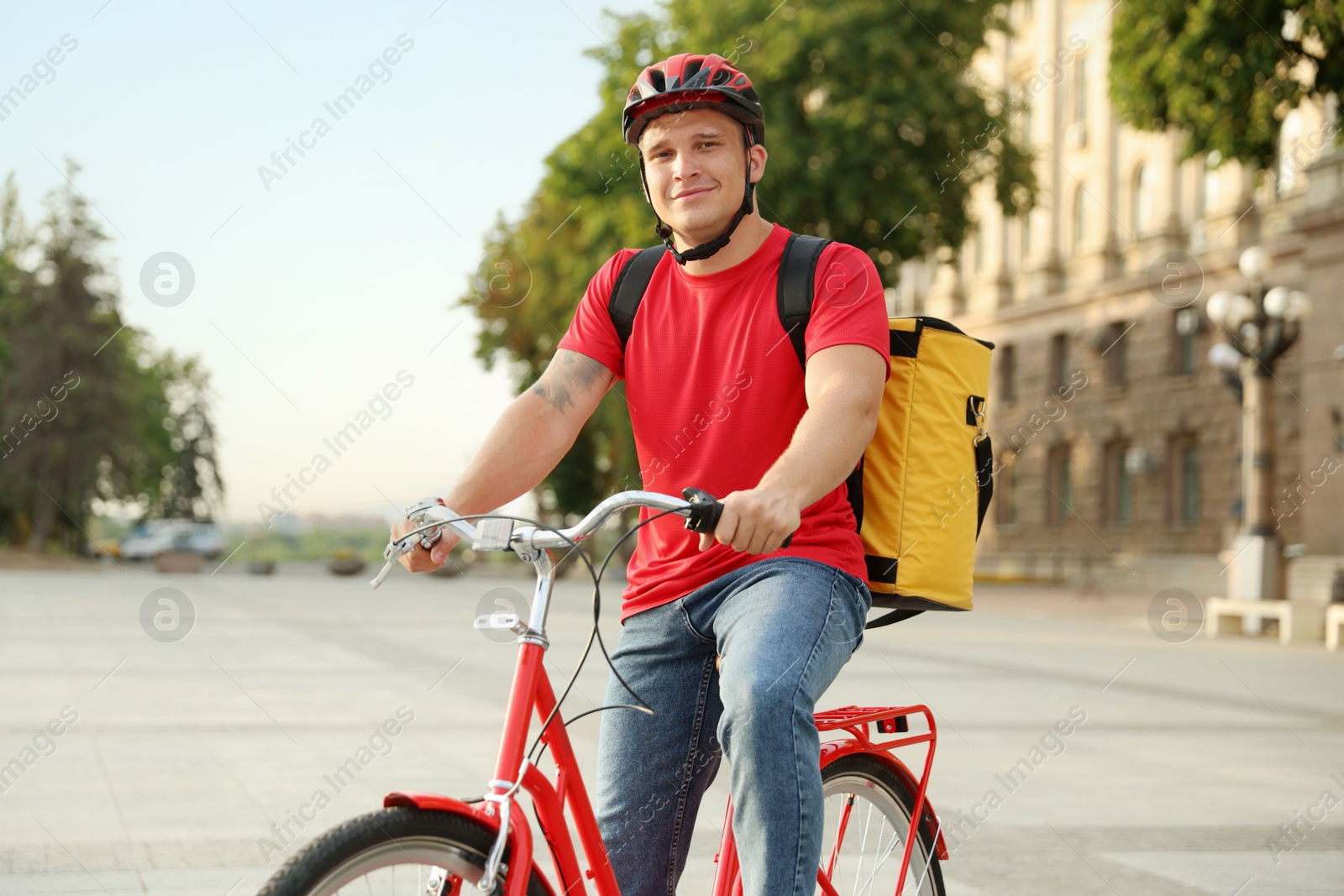 Courier with thermo bag riding bicycle outdoors. Food delivery service Photo of Courier with thermo bag riding bicycle outdoors. Food delivery service