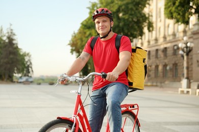 Photo of Courier with thermo bag riding bicycle outdoors. Food delivery service