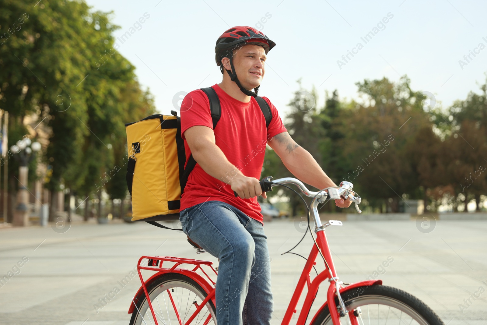 Courier with thermo bag riding bicycle outdoors. Food delivery service Photo of Courier with thermo bag riding bicycle outdoors. Food delivery service