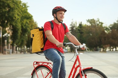 Photo of Courier with thermo bag riding bicycle outdoors. Food delivery service